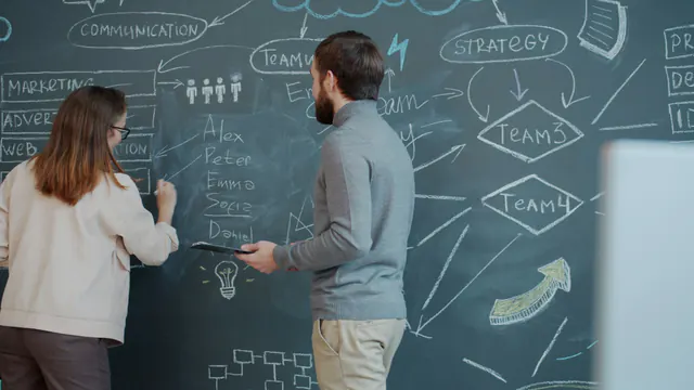 Two colleagues mapping a marketing strategy on a chalkboard